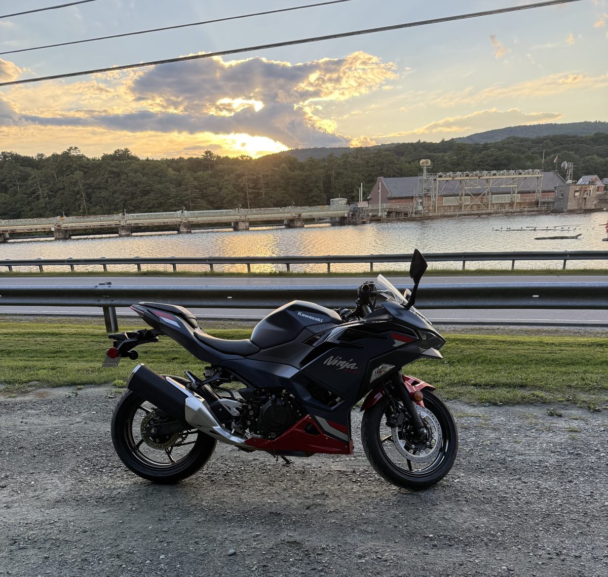 Black and red Kawasaki Ninja parked by a river at sunset